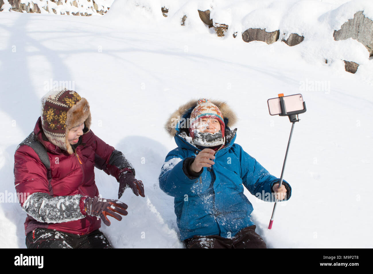 Ein junges Paar ist im Schnee spielen in Seoraksan Nationalpark, Gangwon-do, Südkorea. Das Mädchen warf nur einen Schneeball im Gesicht von ihrem Freund, der Filmen mit einem Smart Phone auf einem selfie stick ist. Seoraksan ist ein schönes und iconic National Park in den Bergen in der Nähe von Sokcho in der Region Gangwon-do in Südkorea. Der Name bezieht sich auf verschneite Felsen bergen. Satz gegen die Landschaft sind zwei Buddhistische Tempel: Sinheung-sa und Beakdam-sa. Diese Region ist Gastgeber der Olympischen Winterspiele im Februar 2018. Seoraksan ist ein schönes und iconic National Park in den Bergen in der Nähe von Sokcho im Stockfoto