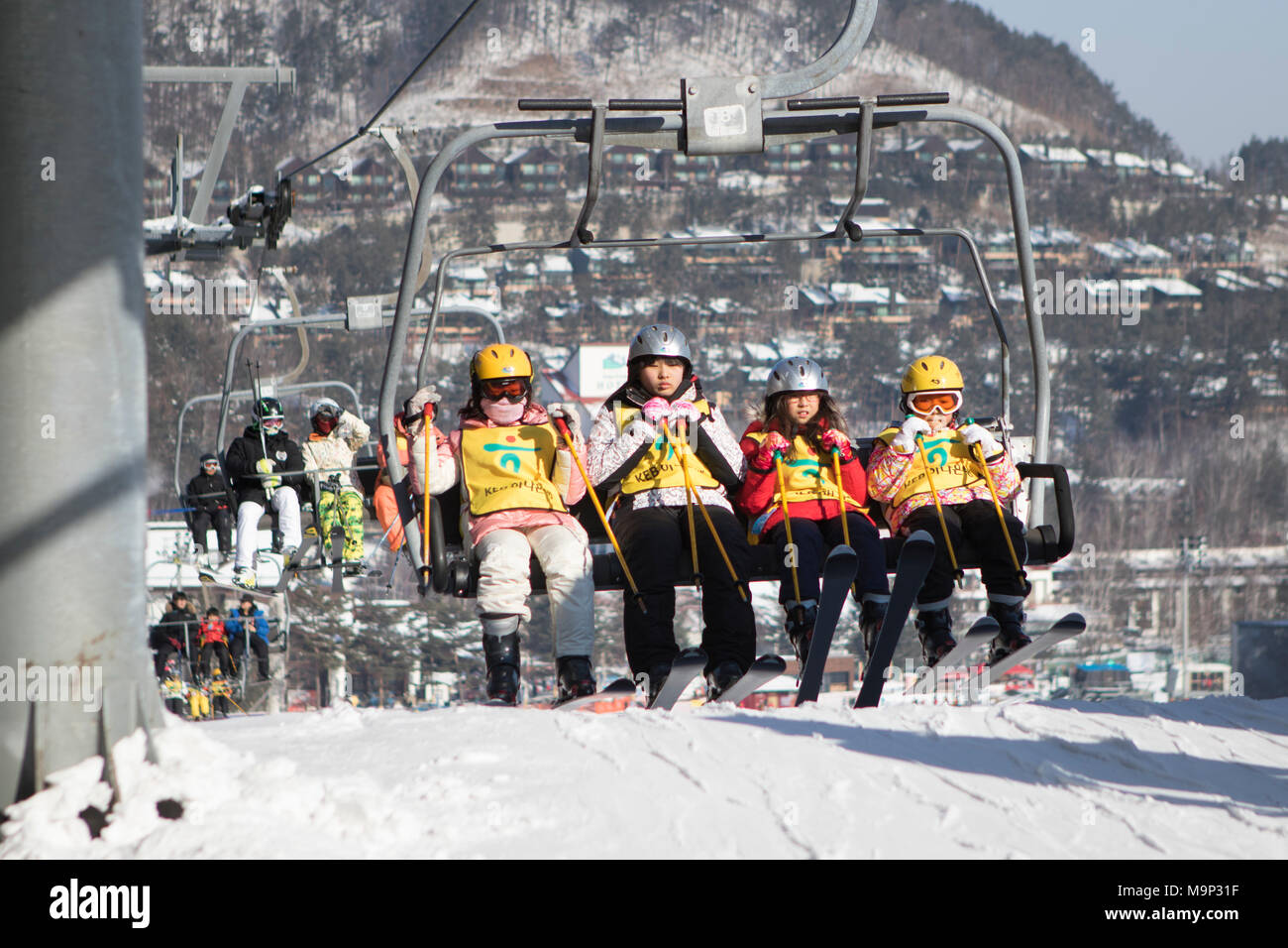 Eine Gruppe von vier Kindern ist bei der Ankunft im Sessellift Bergstation der bunny Neigung an yongpyong. Das Yongpyong-resort (Dragon Valley) Ski Resort ist ein Skigebiet in Südkorea, in Daegwallyeong-myeon, Pyeongchang, Gangwon-do. Es ist die größte Ski- und Snowboard Resorts in Korea. Das Yongpyong-resort bewirten die technischen Ski alpin Veranstaltungen für die olympischen Winterspiele und Paralympics 2018 in Pyeongchang. Einige Szenen der 2002 Korean Broadcasting System drama Winter Sonata wurden im Resort gedreht. Stockfoto