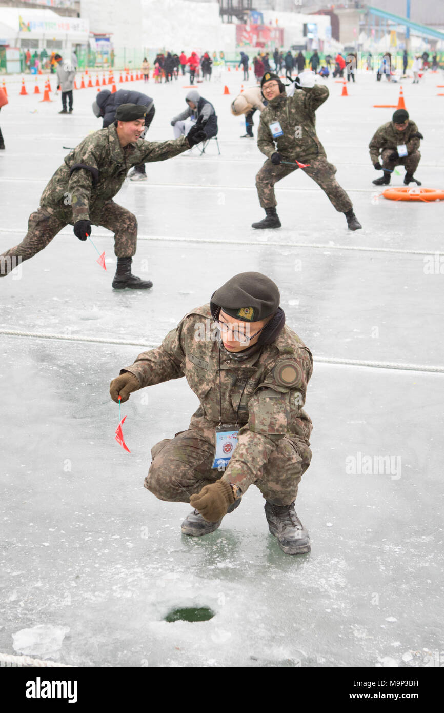 Südkoreanischen Armee Soldaten sind Witze während der Eiszeit Angeln Festival an Hwacheon Sancheoneo in der Region Gangwon-do in Südkorea. Die Hwacheon Sancheoneo Ice Festival ist eine Tradition für die Menschen in Korea. Jedes Jahr im Januar Menschenmassen versammeln sich auf dem zugefrorenen Fluss der Kälte und dem Schnee des Winters zu feiern. Hauptattraktion ist Eisfischen. Jung und Alt warten geduldig auf ein kleines Loch im Eis für eine Forelle zu beißen. In zelten Sie können den Fisch vom Grill, nach dem sie gegessen werden. Unter anderem sind Rodeln und Eislaufen. Die in der Nähe Pyeongchang Region wird Gastgeber der Olympischen Winterspiele in Stockfoto