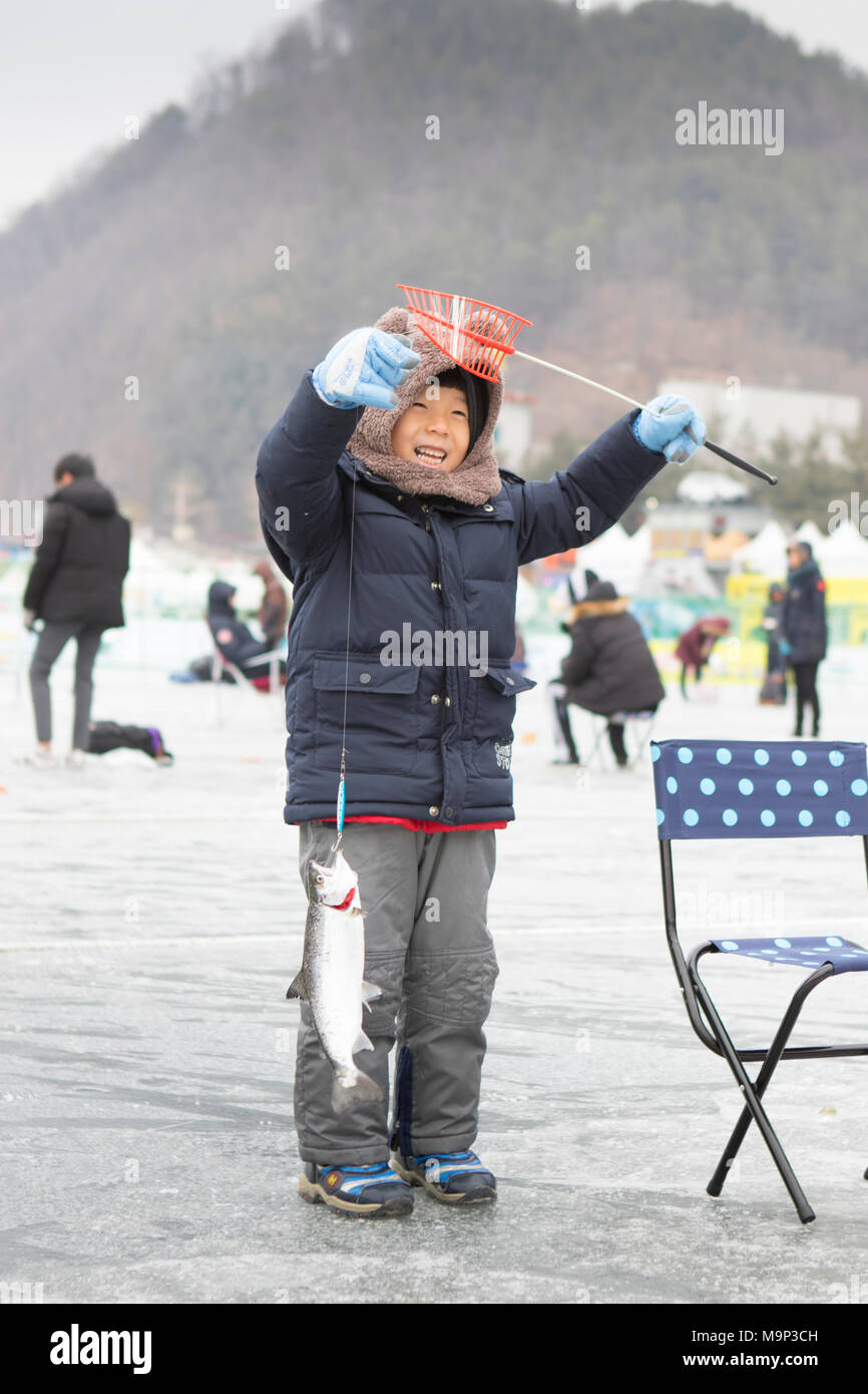 Ein Junge ist glücklich mit dem Fisch, den er während der Eiszeit Angeln Festival an Hwacheon Sancheoneo gefangen in der Gangwon-do-Region von Südkorea. Die Hwacheon Sancheoneo Ice Festival ist eine Tradition für die Menschen in Korea. Jedes Jahr im Januar Menschenmassen versammeln sich auf dem zugefrorenen Fluss der Kälte und dem Schnee des Winters zu feiern. Hauptattraktion ist Eisfischen. Jung und Alt warten geduldig auf ein kleines Loch im Eis für eine Forelle zu beißen. In zelten Sie können den Fisch vom Grill, nach dem sie gegessen werden. Unter anderem sind Rodeln und Eislaufen. Die in der Nähe Pyeongchang Region wird Gastgeber der Winter Stockfoto