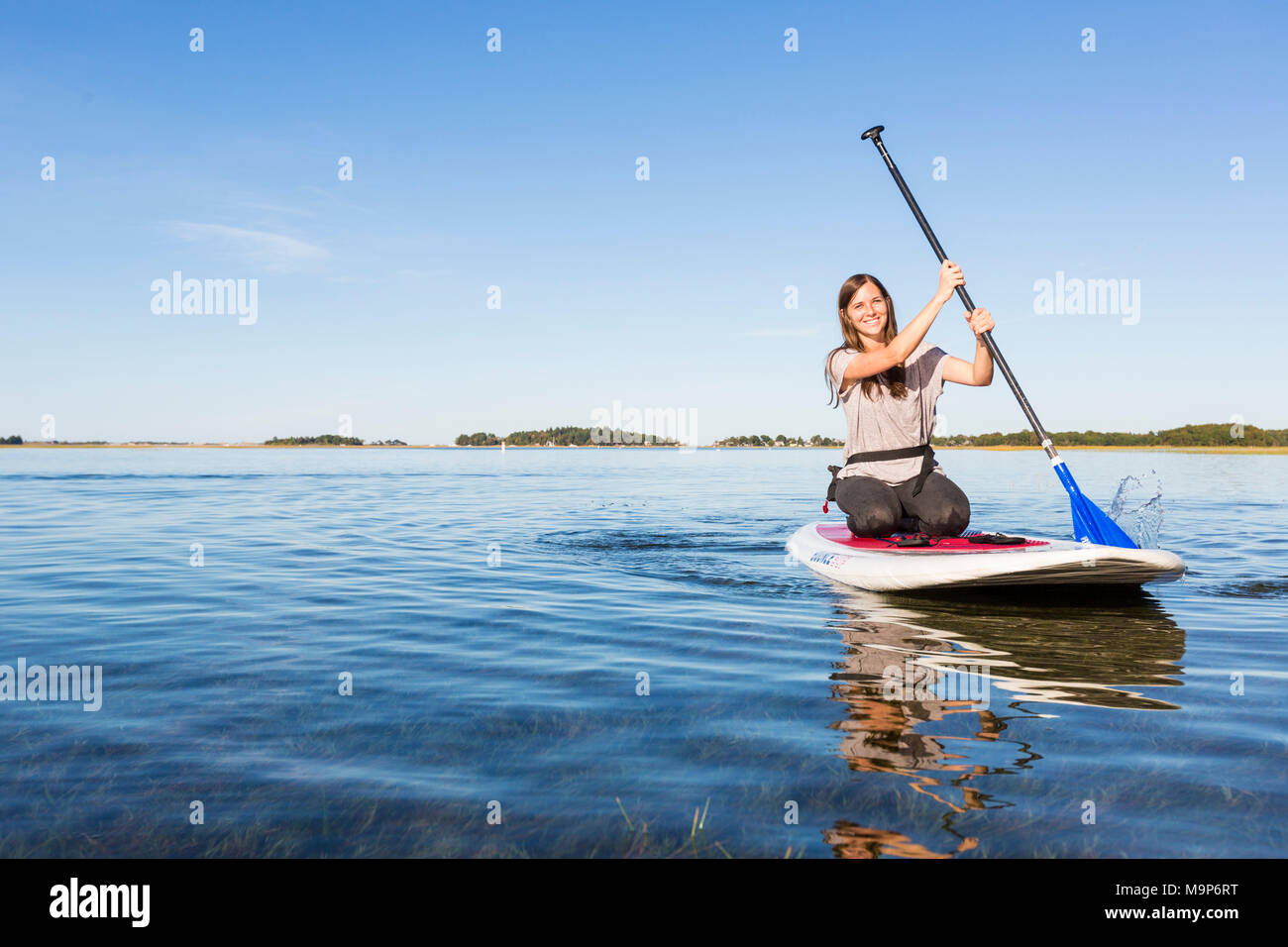 Frau stehend Paddle Boarding auf Essex River bei Cox Reservierung, Essex, Massachusetts Stockfoto