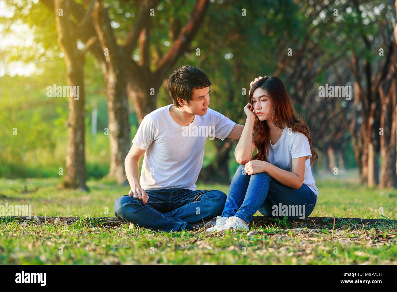 Unglückliche Frau sitzend mit einem betroffenen Kerl trösteten im Park Stockfoto