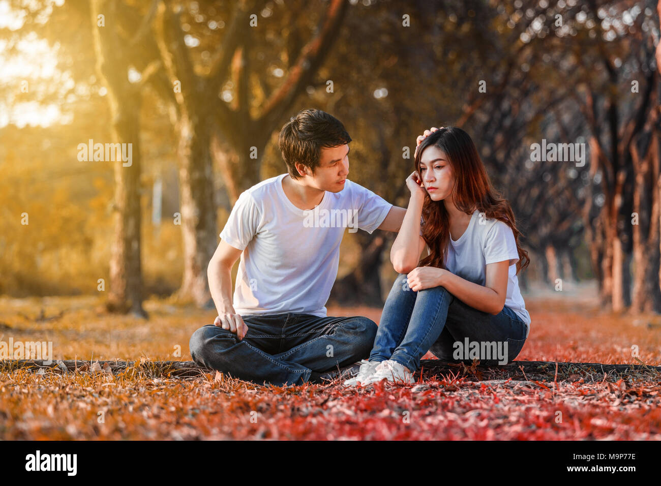 Unglückliche Frau sitzend mit einem betroffenen Kerl trösteten im Park Stockfoto