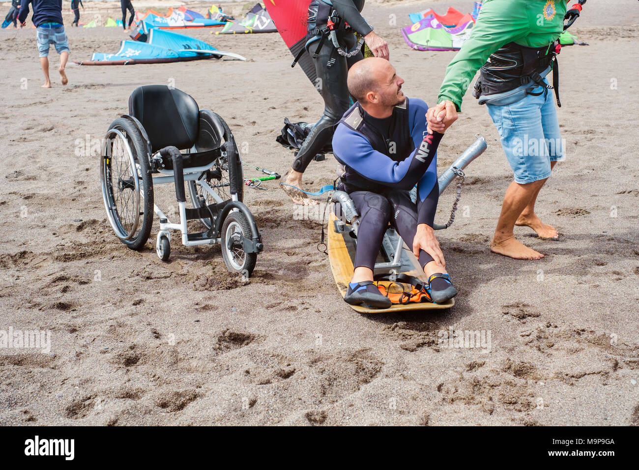 Ein behinderter Kite Surfer erhält vorbereitet, das aus dem Meer zu gehen Stockfoto