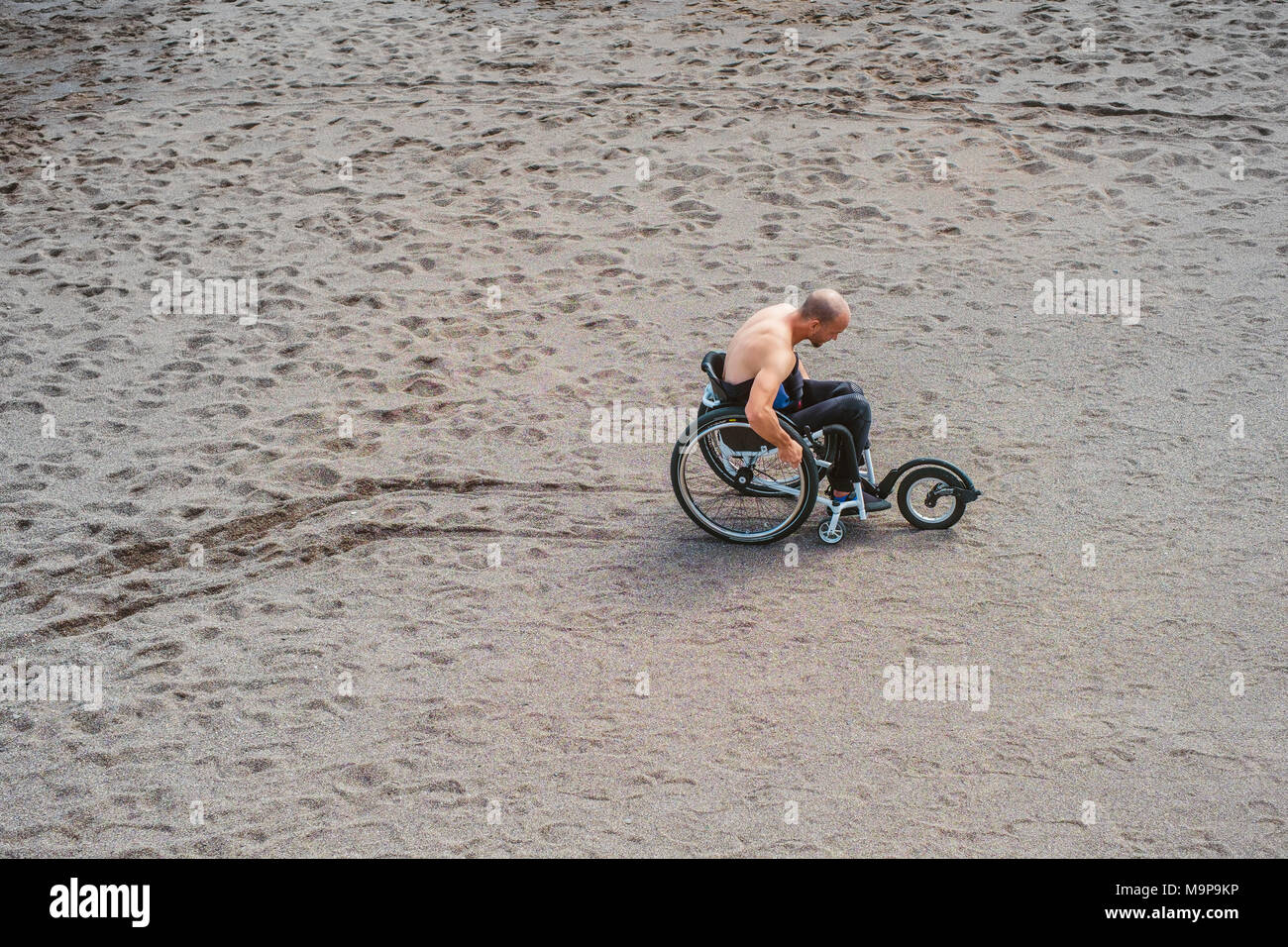 Eine behinderte Person drückt seinem Rollstuhl auf den Strand Stockfoto