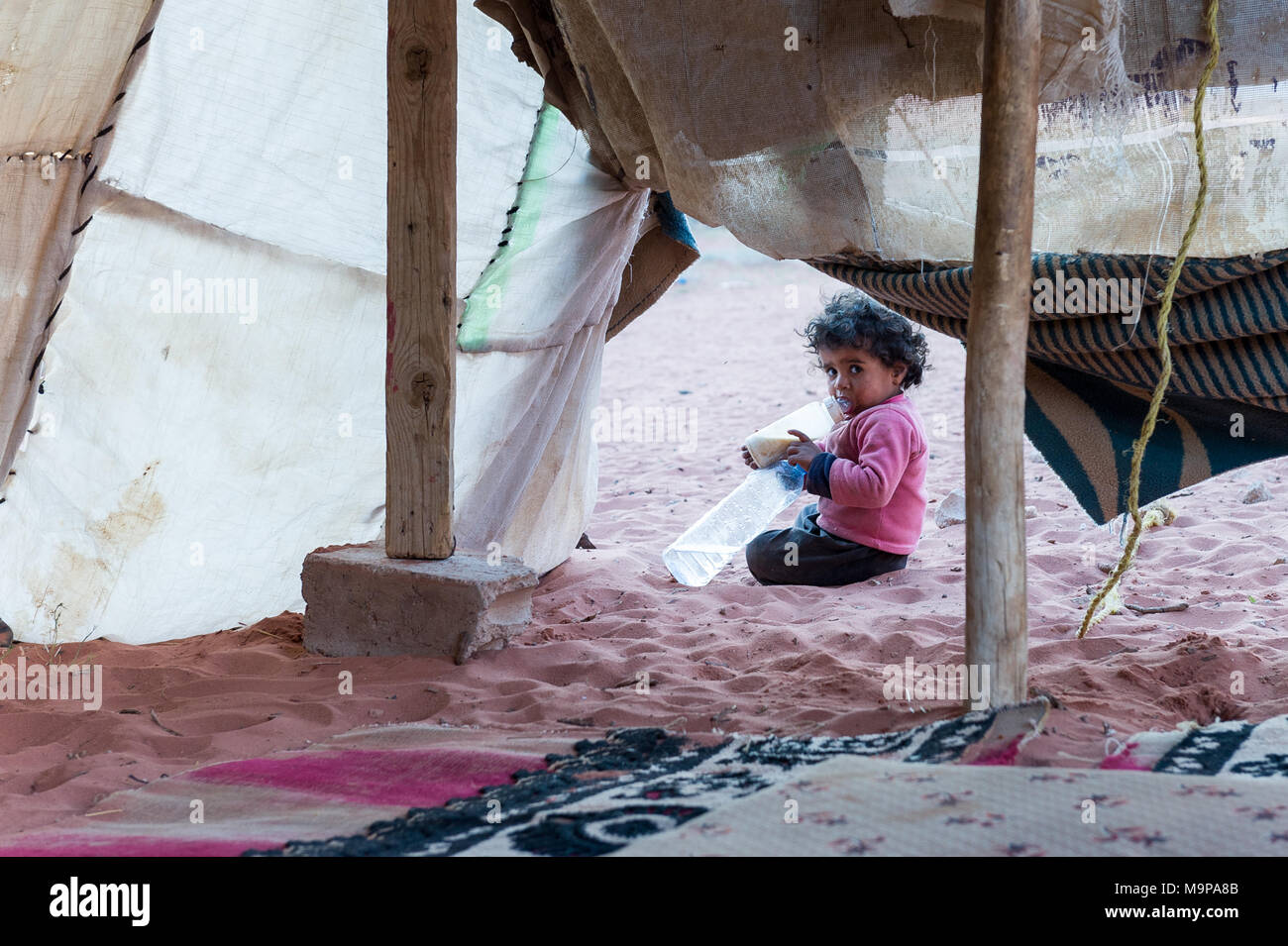 Bedouin Baby spielen und trinken in einem Beduinenzelt in der Nähe von De Grenze von Sausi-Arabia. Stockfoto