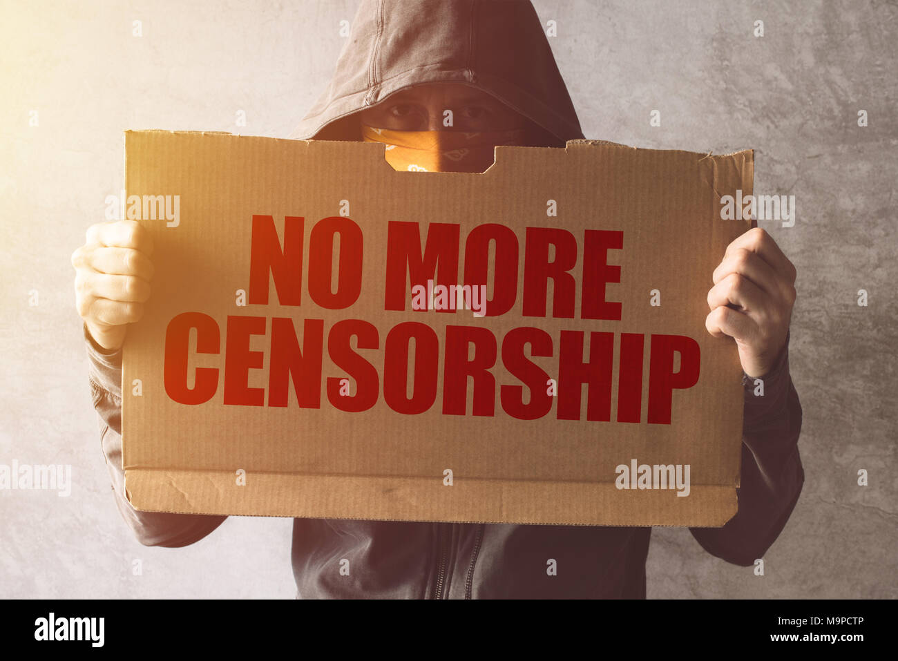 Hooded Aktivist Demonstrant Holding nicht mehr Zensur Protest anmelden. Mann mit Kapuze und Schal über Gesicht in Aktivismus und kämpfen für die Ca Stockfoto