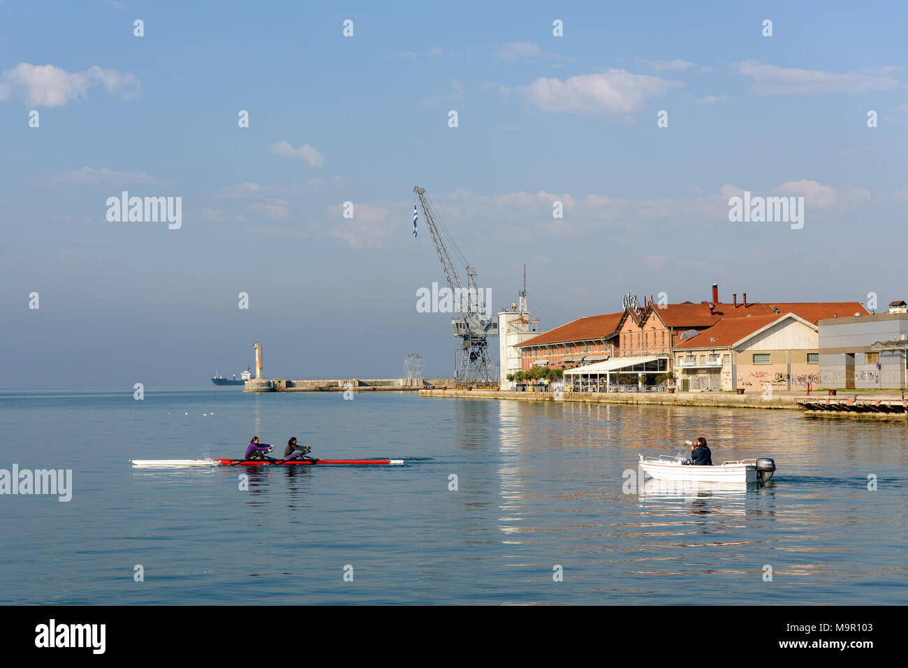 Thessaloniki, Griechenland - 15. April 2017: rudergeräte Training in den frühen Morgenstunden auf das ruhige Wasser der Ägäis mit dem Hafen von Thessaloniki im zurück Stockfoto