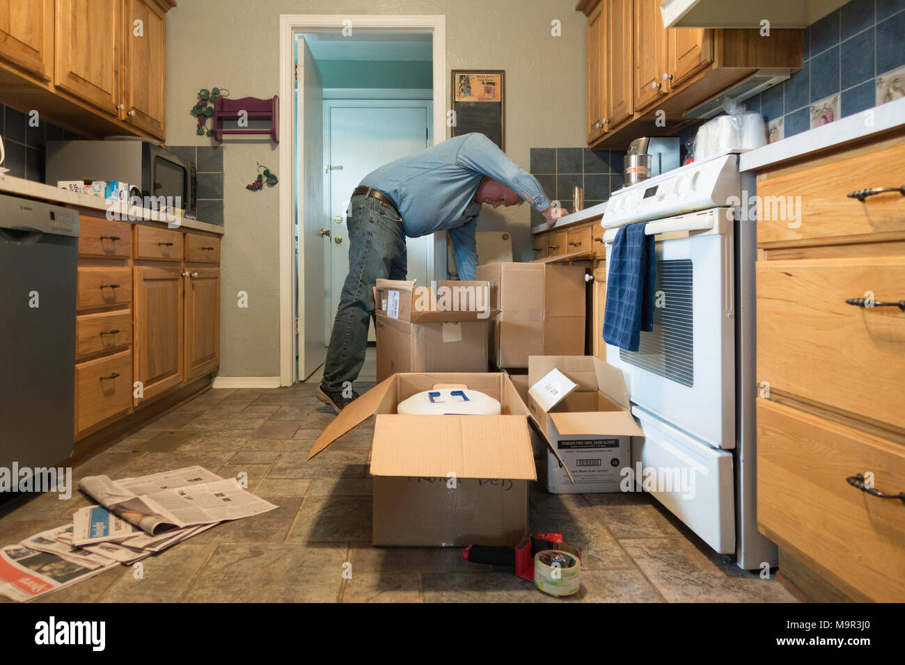 Ein 50 Jahre alter Kaukasischer mann Packs bis Küche liefert in Boxen für einen bevorstehenden Umzug von Oklahoma City, Oklahoma, USA. Stockfoto