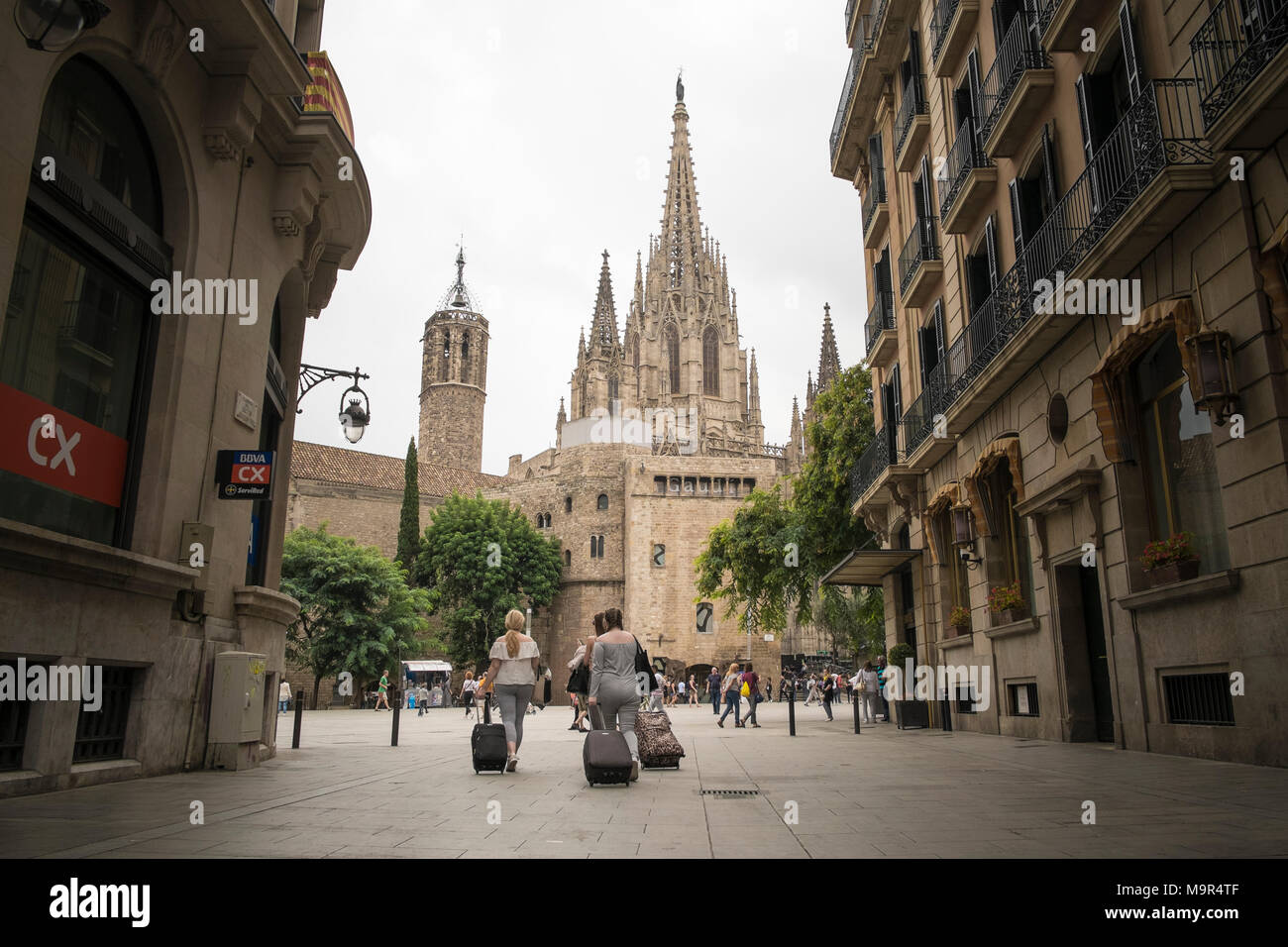 Drei weibliche Reisende mit ihrem Gepäck zu Fuß eine Straße in Barcelona auf die Kathedrale von Barcelona Stockfoto