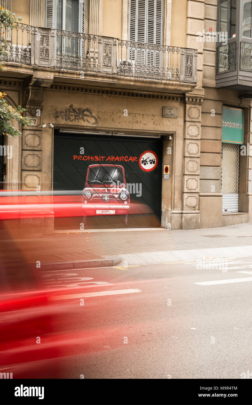 Bewegungsunschärfe auf ein Auto beschleunigt Vergangenheit eine künstlerische "Parken verboten" Schild auf ein Garagentor gemalt, in Barcelona, Spanien. Rote Farbe Thema. Stockfoto
