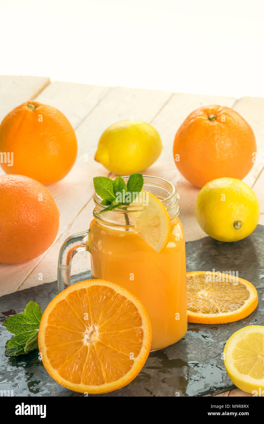 Frisch gepresster Orangensaft in einem Glas, von Orangen und Zitronen Scheiben in einem warmen Sommer Licht umgeben Stockfoto