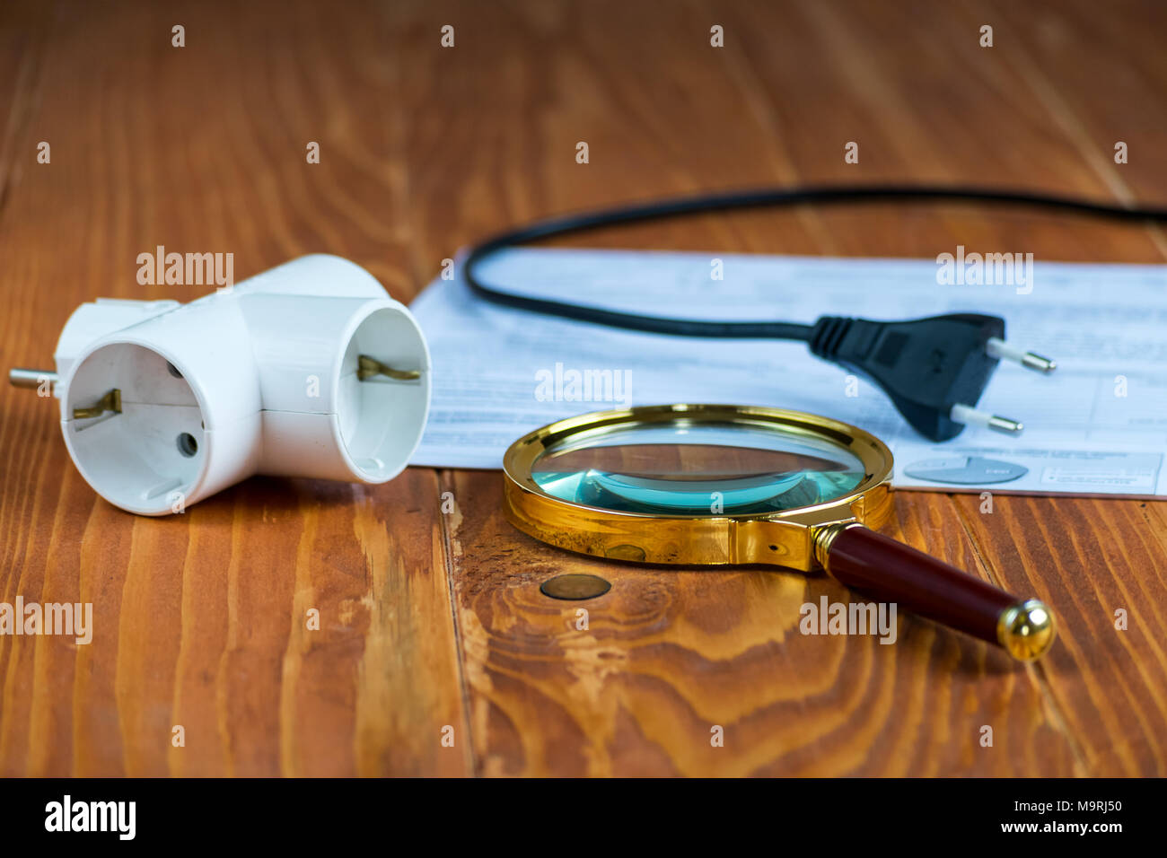 Stromrechnung auf einem Holztisch mit Lupe und Elektrische Splitter Stockfoto