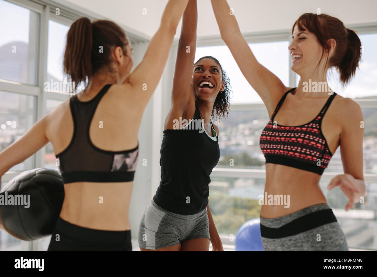 Freundliche Frauen mit Medizinball ihre Hände zusammen im Fitness Studio. Mädchen hoch fünf Nach erfolgreichem Training Session. Stockfoto