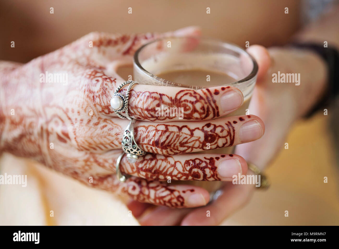 Weibliche Hände dekorativ durch Henna mit Tasse Masala Tee farbige Stockfoto