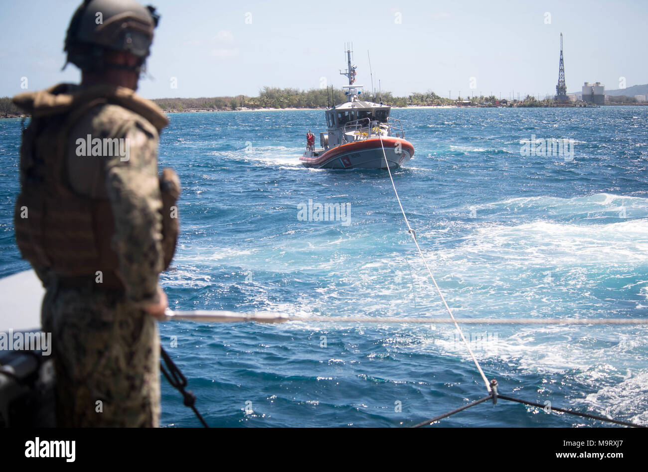Ein Seemann, der an die in den Küstenzonen Riverine Squadron (CRS) 4, Det zugeordnet. Guam Uhren als Mark VI Patrouillenboot schleppt ein 47-Fuß-Motor Rettungsboot zugewiesen der U.S. Coast Guard Sektor Guam während einer abschleppen Übung in der Apra Harbor, Guam, 28. März 2018. CRS-4, Det. Guam ist zum Kommandanten, Task Force 75, die primäre Expeditionary task force verantwortlich für die Planung und Ausführung der Küstengebiete Riverine operations, Beseitigung von Explosivstoffen, tauchen Engineering und Bau zugeordnet und Unterwasser Bau in den USA 7 Flotte Bereich der Operationen. (U.S. Marine bekämpfen Kamera Foto von Mass Communication Specialist 1. Stockfoto