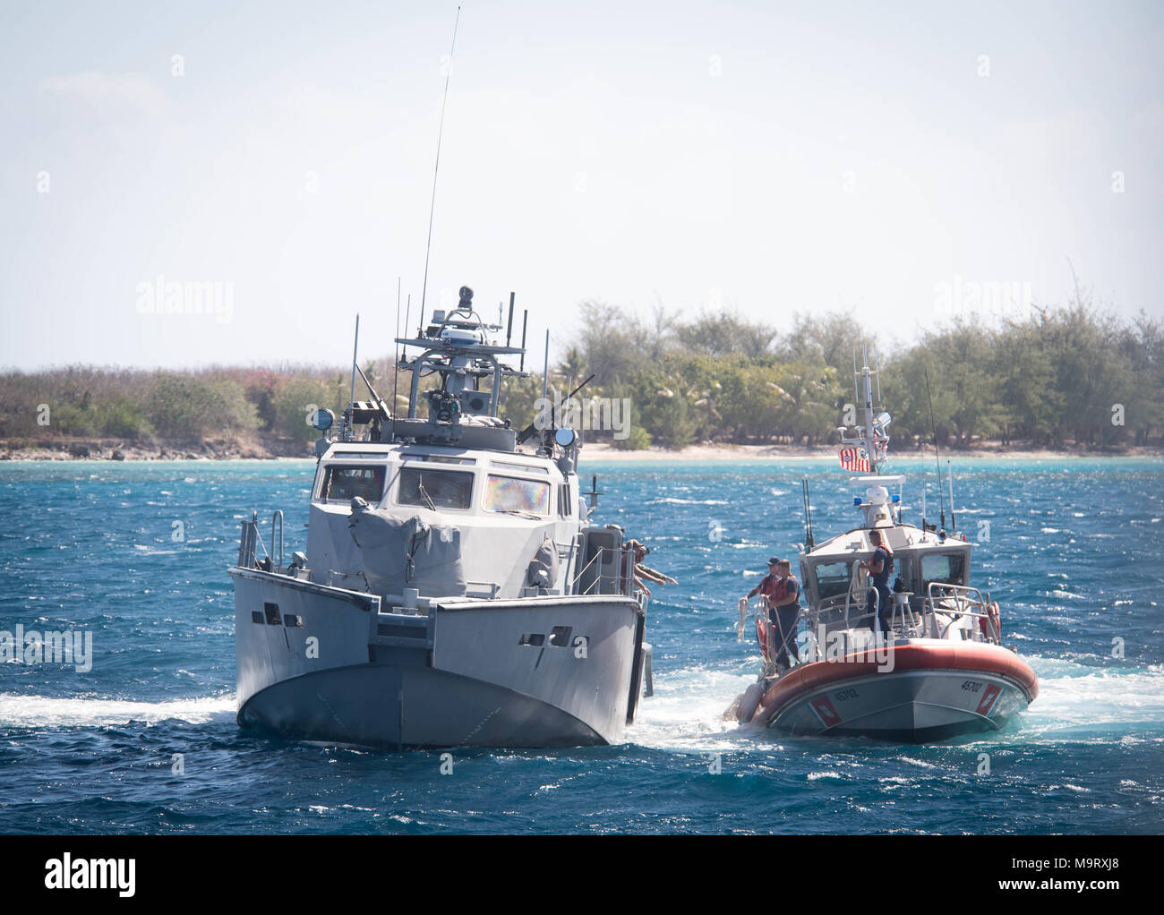 Segler von Coastal Riverine Squadron (CRS) 4, Det zugeordnet. Guam erreichen für eine Linie von der U.S. Coast Guard Matrosen an Bord eines 47-Fuß-Motor Rettungsboot, zu der U.S. Coast Guard Sektor Guam zugeordnet, während ein Abschleppen Übung in der Apra Harbor, Guam, 28. März 2018. CRS-4, Det. Guam ist zum Kommandanten, Task Force 75, die primäre Expeditionary task force verantwortlich für die Planung und Ausführung der Küstengebiete Riverine operations, Beseitigung von Explosivstoffen, tauchen Engineering und Bau zugeordnet und Unterwasser Bau in den USA 7 Flotte Bereich der Operationen. (U.S. Marine bekämpfen Kamera Foto von Masse Kommuniz Stockfoto