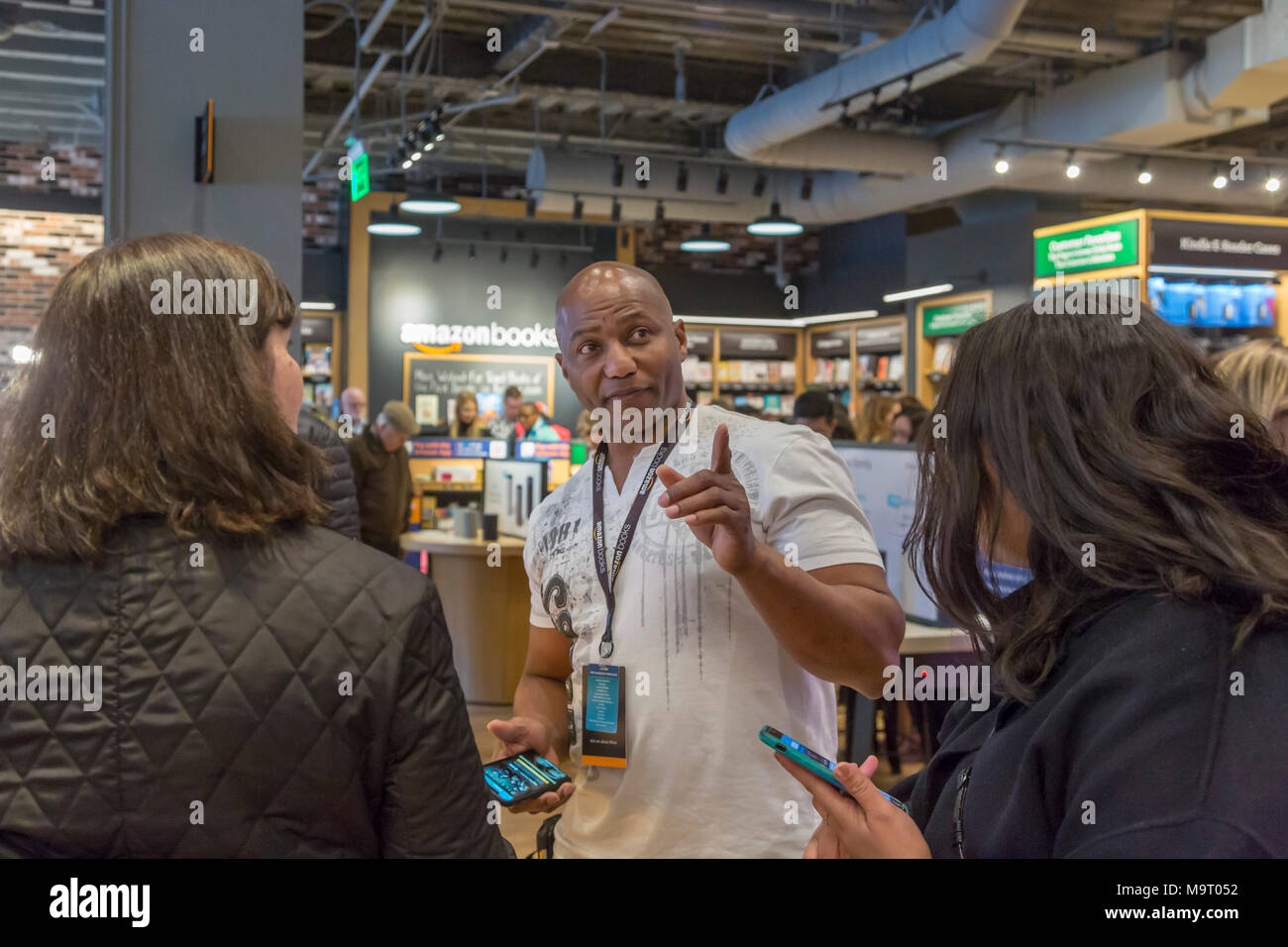 Washington, DC - Amazon's Buchhandlung in Washingtons Stadtteil Georgetown. Assistant Store Manager John Kürzere zeigt Kunden, wie ein Buch zu prüfen." Stockfoto