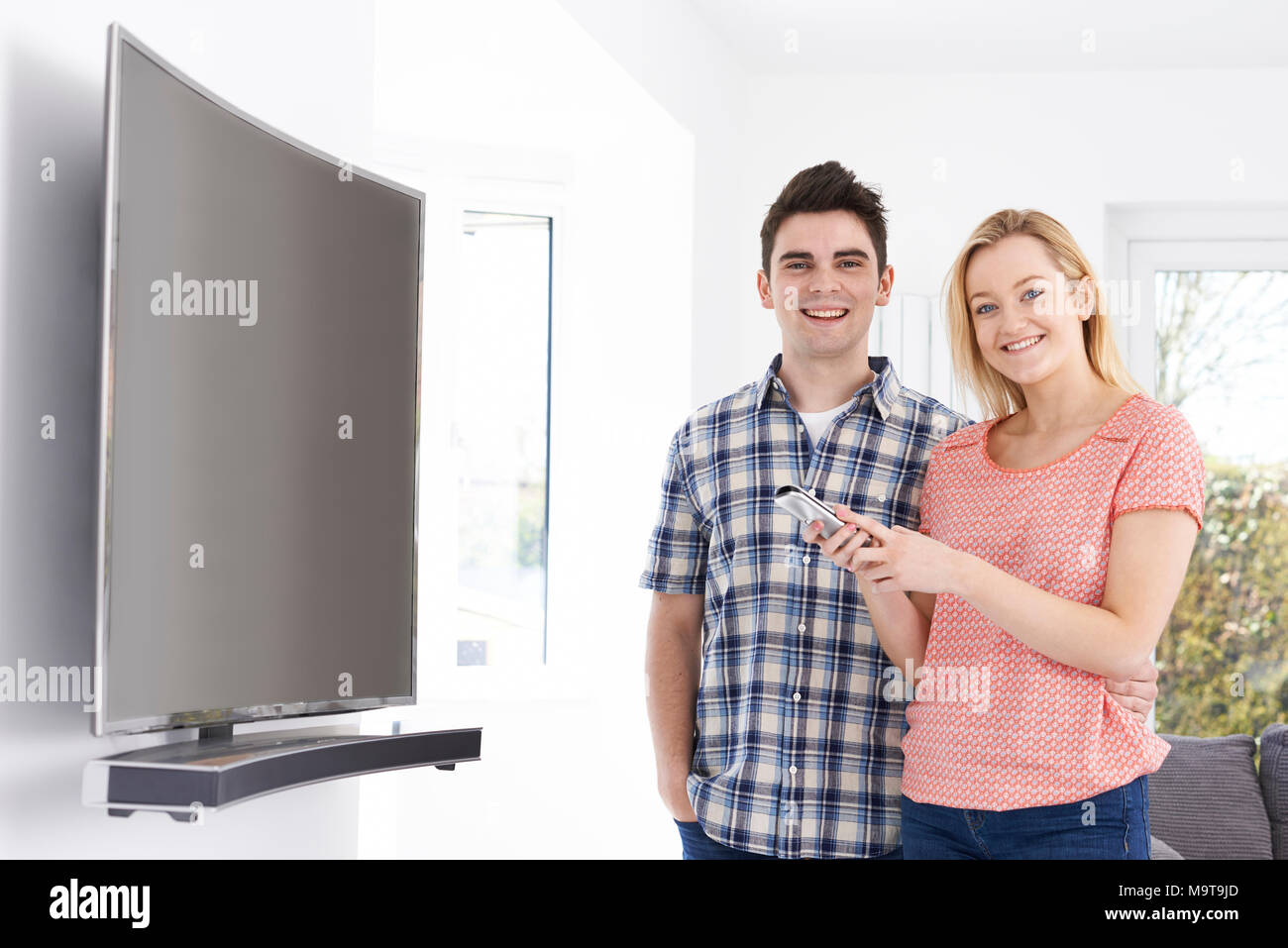 Porträt eines jungen Paares mit Neuen gekrümmten Leinwand Fernsehen zu Hause Stockfoto