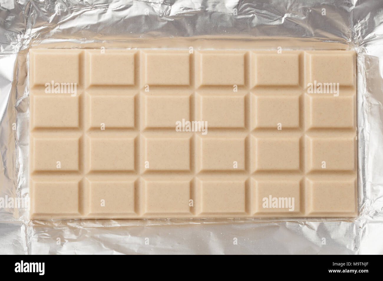 Ganze bar von milchig weiße Schokolade in einem offenen Metallic Folie Verpackung Stockfoto