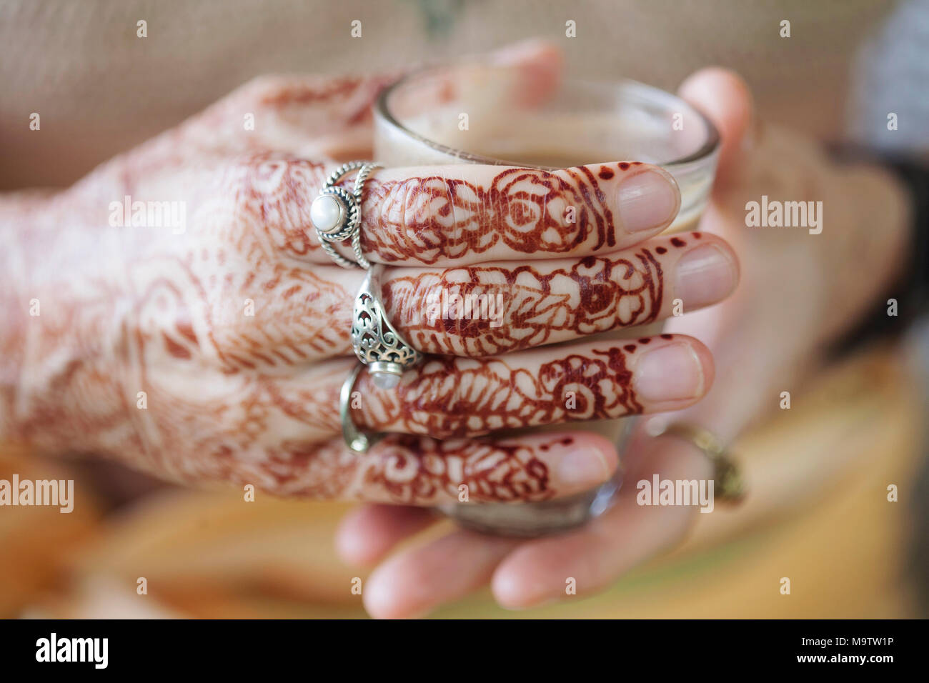 Weibliche Hände dekorativ durch Henna mit Tasse Masala Tee farbige Stockfoto