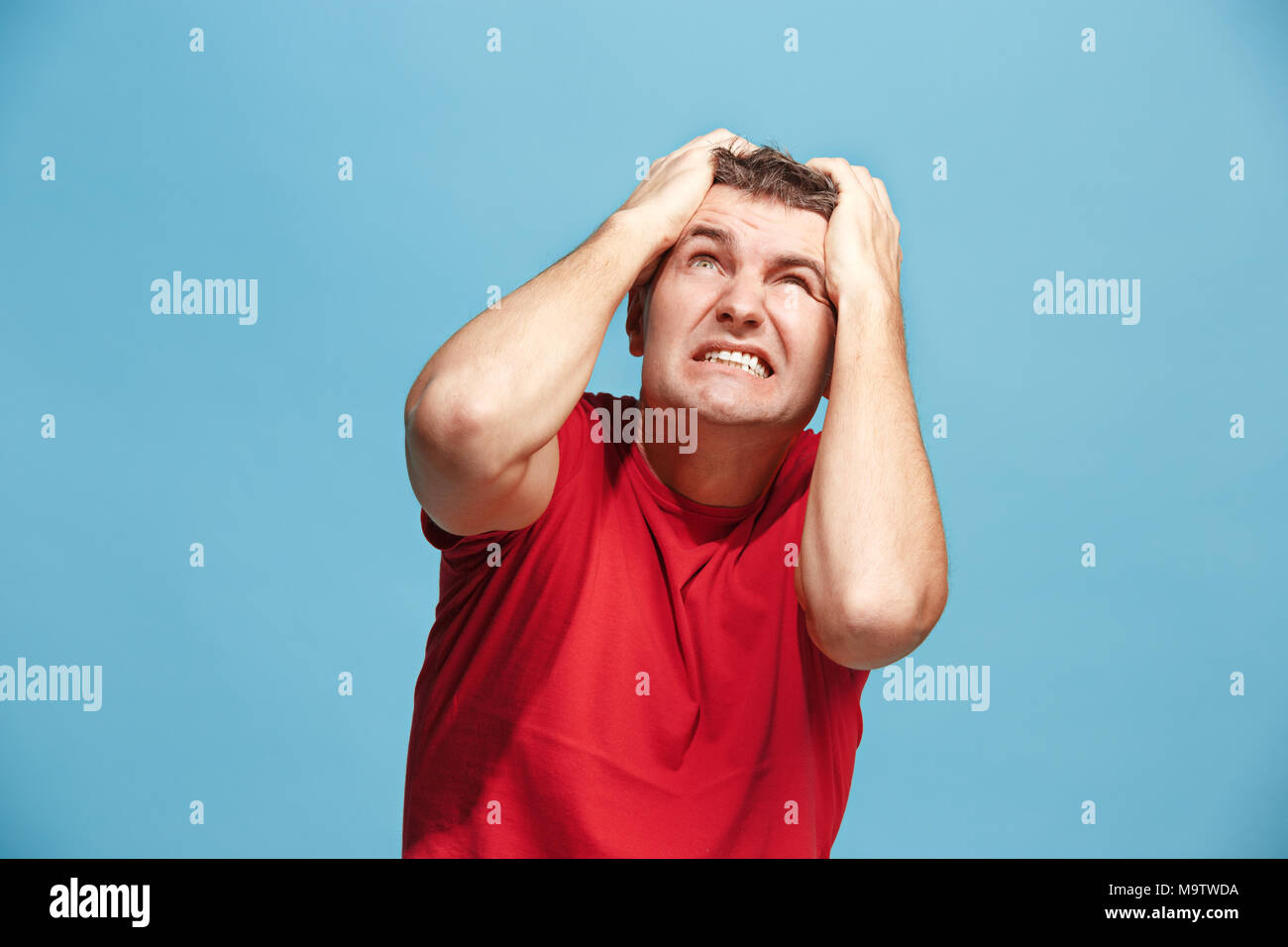 Schöner Mann im Stress isoliert auf Blau Stockfoto