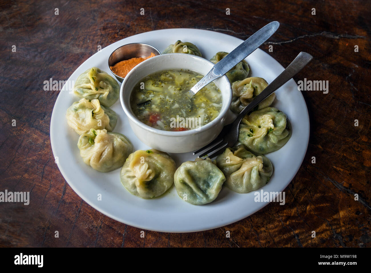 Nepalesische traditionelle Knödel momos mit Tomate chatni und heiße Suppe serviert. Stockfoto