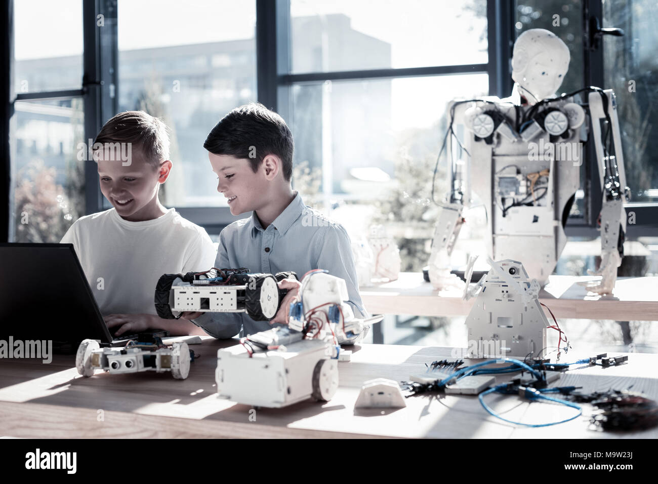 Frohe Kinder arbeiten in Werkstatt und programmieren Roboter Maschinen  Stockfotografie - Alamy