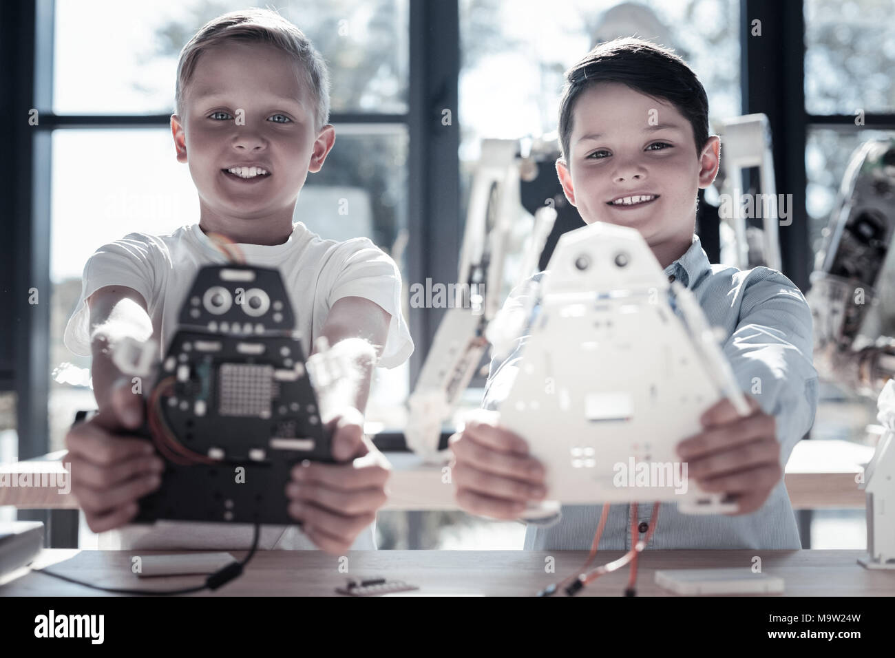 Zufriedene jugendliche Jungen zeigen ihre Roboter Maschinen Stockfoto