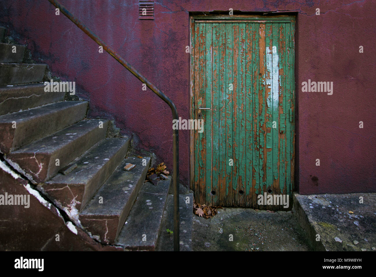 Grüne alte Tür auf magenta Wand mit Treppen an der Seite Stockfoto