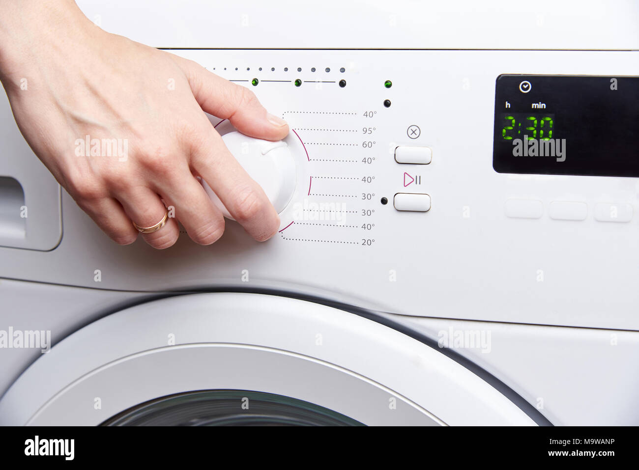 Die Hand einer Frau startet eine Waschmaschine Stockfoto