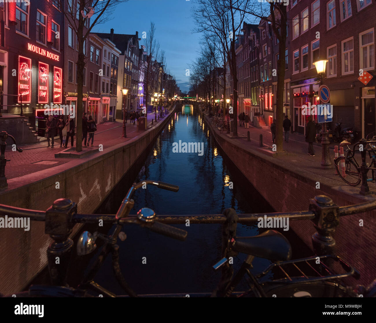 Abend blaue Stunde zeit Blick hinunter Oudezijds Achterburgwal Canal Street in der weltberühmten Rotlichtviertel von Amsterdam, Niederlande. Stockfoto