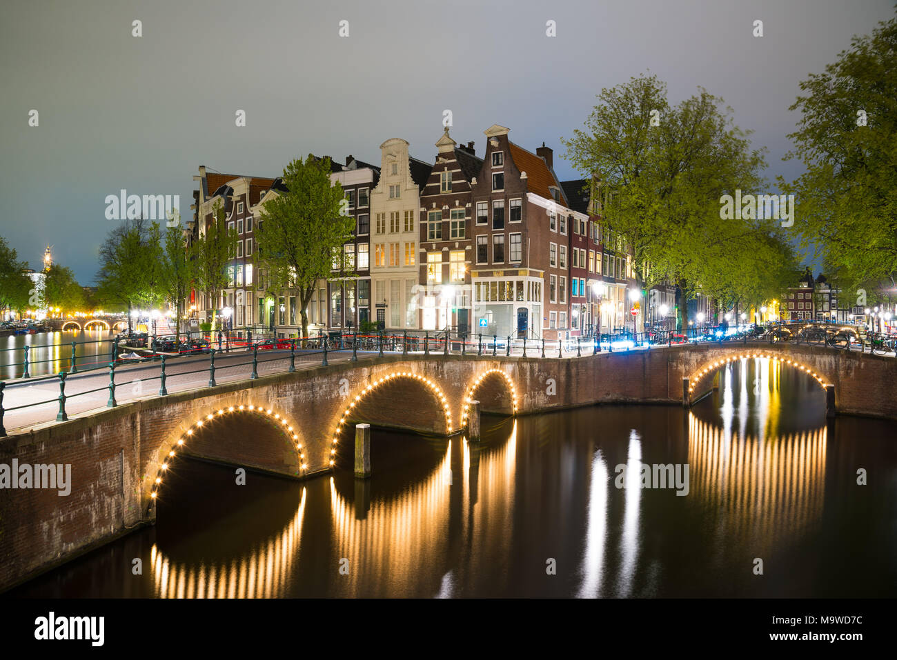 Amsterdam Canal, die Brücke und die typischen Häuser in der Abenddämmerung blaue Stunde, Holland, Niederlande. Stockfoto