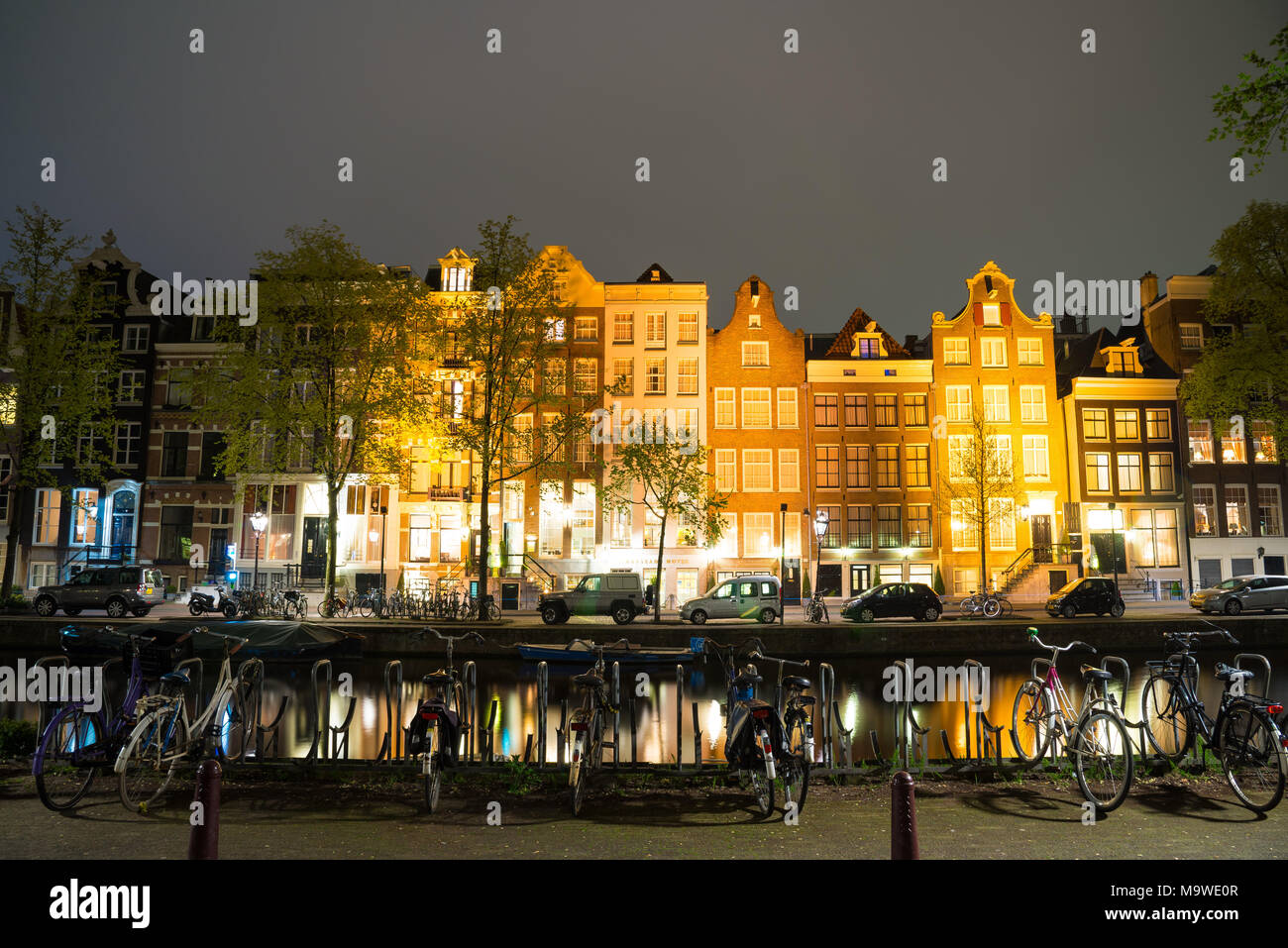 Nacht Ausblick auf Amsterdam Stadtbild mit Canal, die Brücke und die mittelalterlichen Häuser in der Dämmerung beleuchtet. Amsterdam, Niederlande Stockfoto