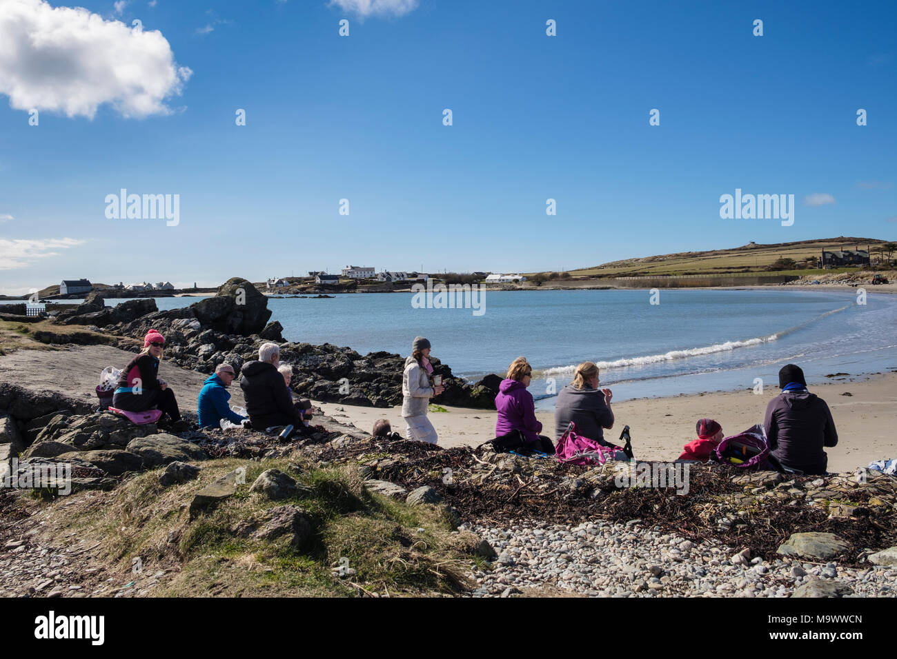 Gruppe der Wanderer eine Pause zum Mittagessen mit Blick über Borthwen Strand. Rhoscolyn, Holy Island, Isle of Anglesey, North Wales, UK, Großbritannien Stockfoto