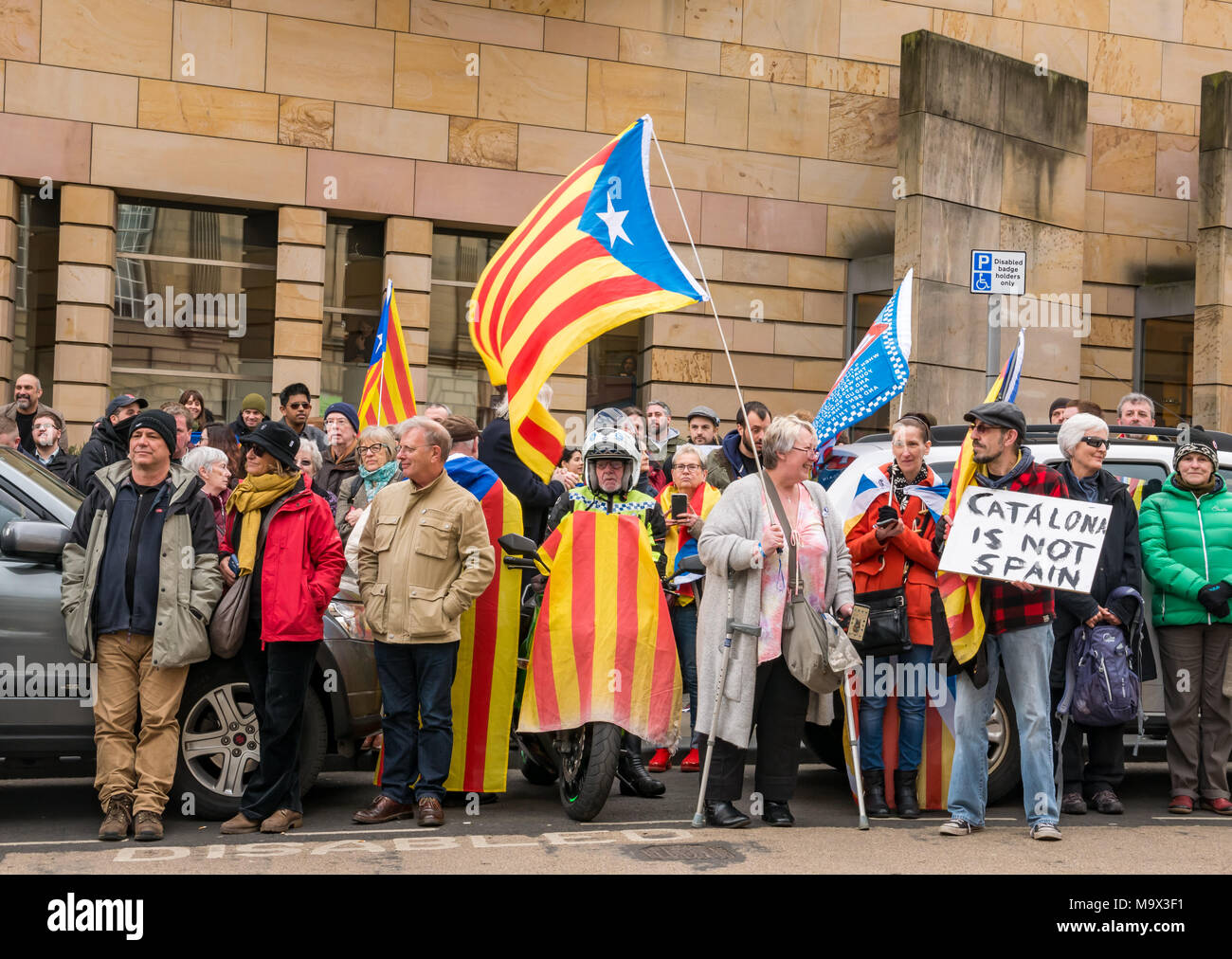 Edinburgh, Schottland, Großbritannien, 28. März 2018. Die Demonstranten und Unterstützer von Professor Clara Ponsati winken Katalanischen flags ausserhalb von Edinburgh Sheriff Court, Chambers Street, wie Clara Ponsati, ehemalige katalanische Bildungsminister, in einer ersten Auslieferung Anhörung vor Gericht erscheint. Demonstranten enthalten die schottische Unabhängigkeit Unterstützer. Ein männlicher Demonstrant hält ein Plakat lesen "Catalona ist nicht Spanien". Ein Motorradfahrer mit einem katalanischen Flagge über das Motorrad drapiert Stockfoto