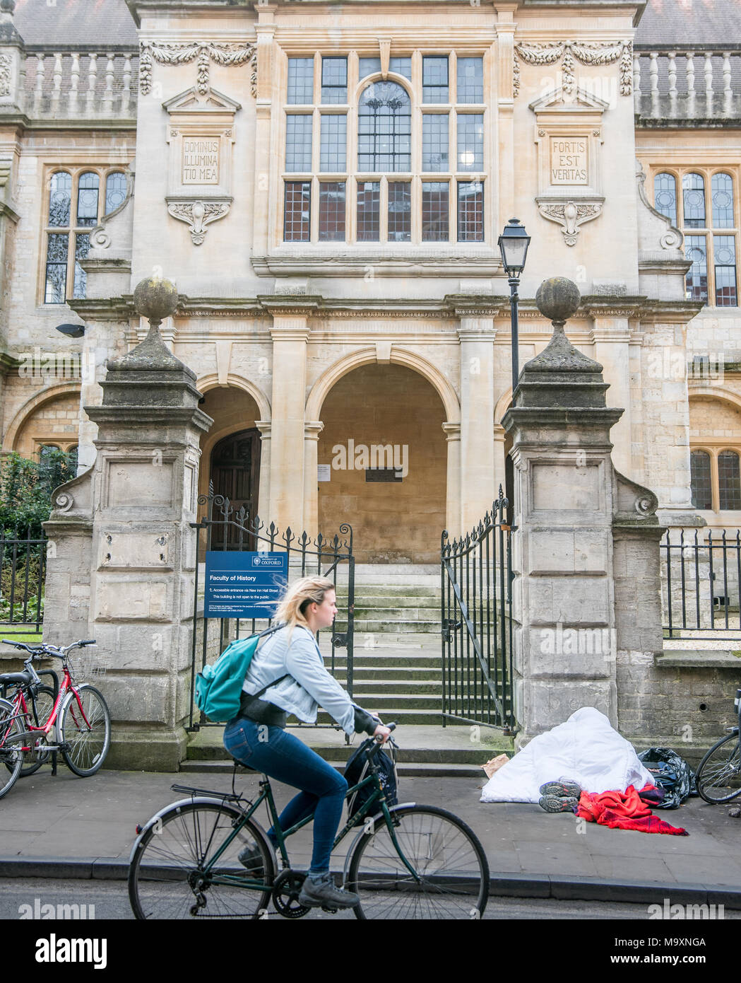 Eine obdachlose Person schläft auf dem Bürgersteig vor dem Eingang zum historischen Fakultät der Universität in der Stadt Oxford, England, an einem Wintertag Stockfoto