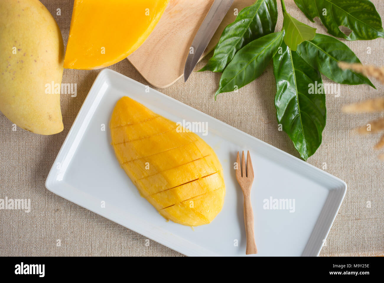 Mango Slices auf weiße Platte mit frischer Mango und Blätter, Ansicht von oben Bild Stockfoto