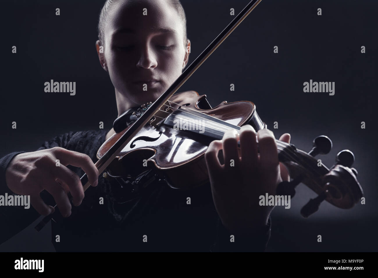 Junge Frau Spielen der Violine vor einem dunklen Hintergrund. Studio shot Stockfoto