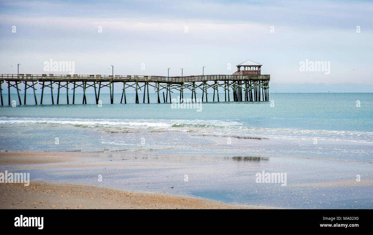 Sunrise mit dem Atlantic Beach Pier im Hintergrund mit Sand, das Meer, die Wellen und die blauen Wolken Stockfoto