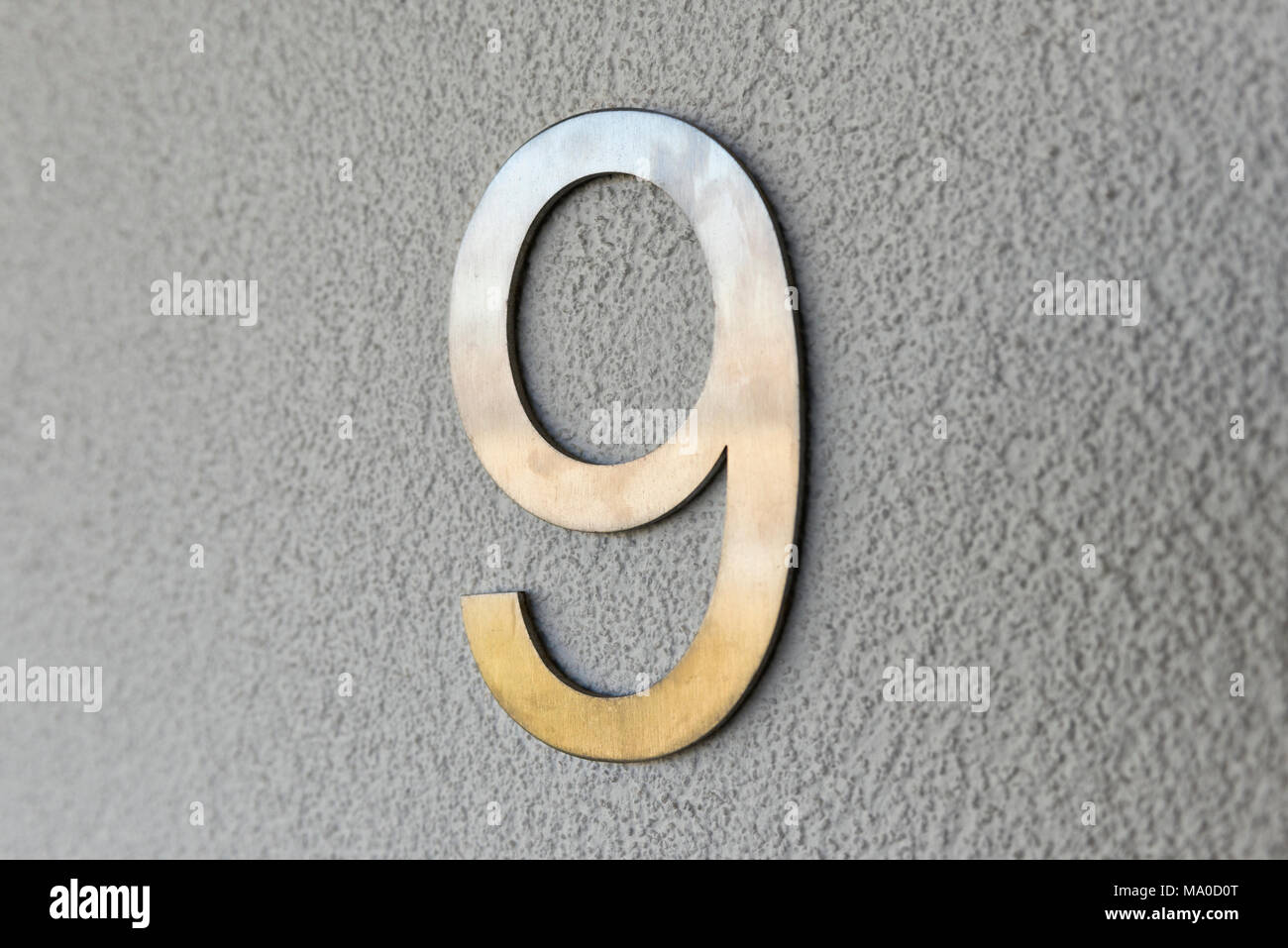 Ein Edelstahl Nummer neun auf die graue Wand eines Hauses angebracht, um die Eigenschaften der Adresse. Stockfoto