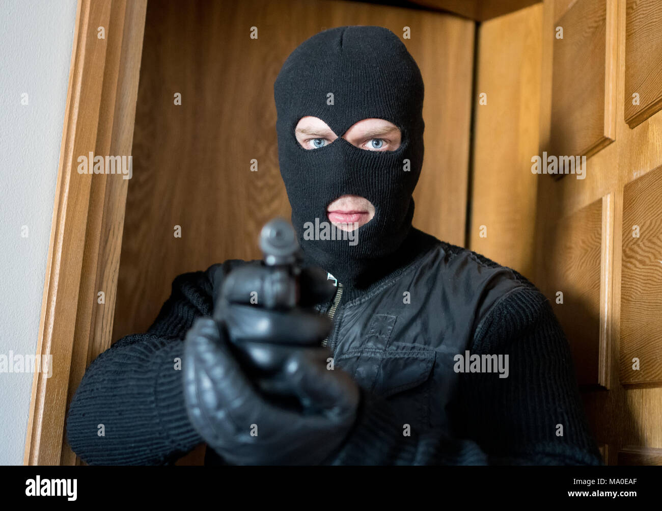 Bewaffneter Mann in Balaclava stehen in der Nähe der Tür und darauf abzielen. Stockfoto