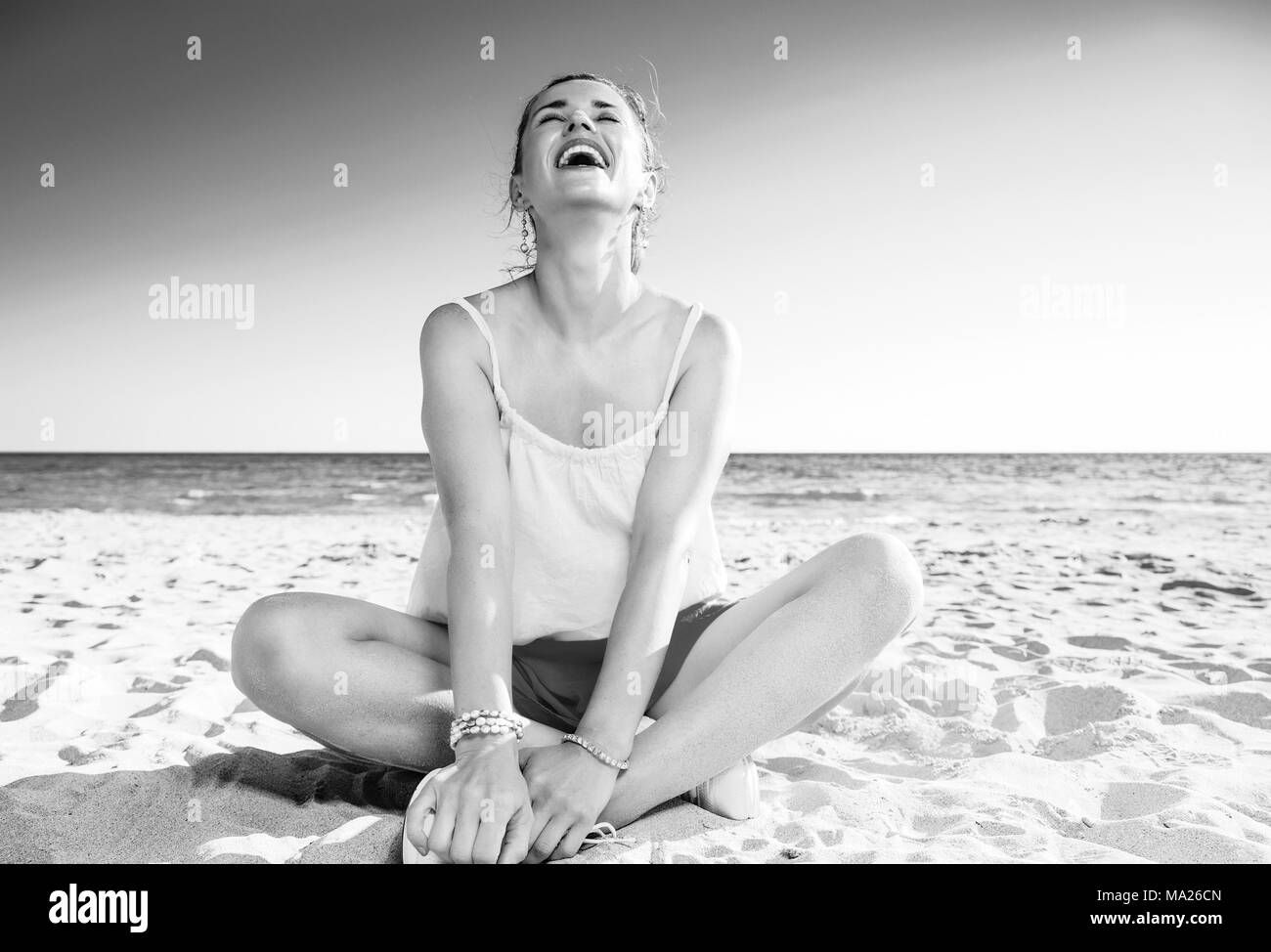 Bunt und wunderbar Gelaunt. Entspannt trendy Frau in Buntes Kleid sitzt auf der Seeküste Stockfoto