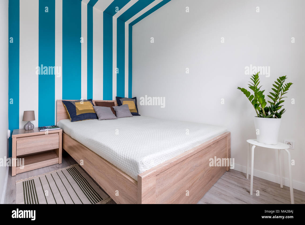 Modernes Schlafzimmer mit Doppelbett und gestreifte Wand in Weiß und Blau Stockfoto
