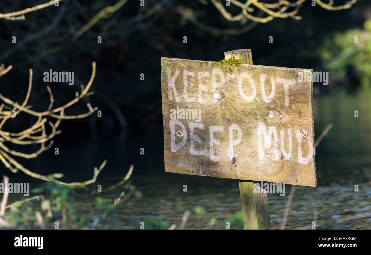 Halten Sie tiefer Schlamm Gefahr Warnschild in einem schlammigen See in Großbritannien. Stockfoto