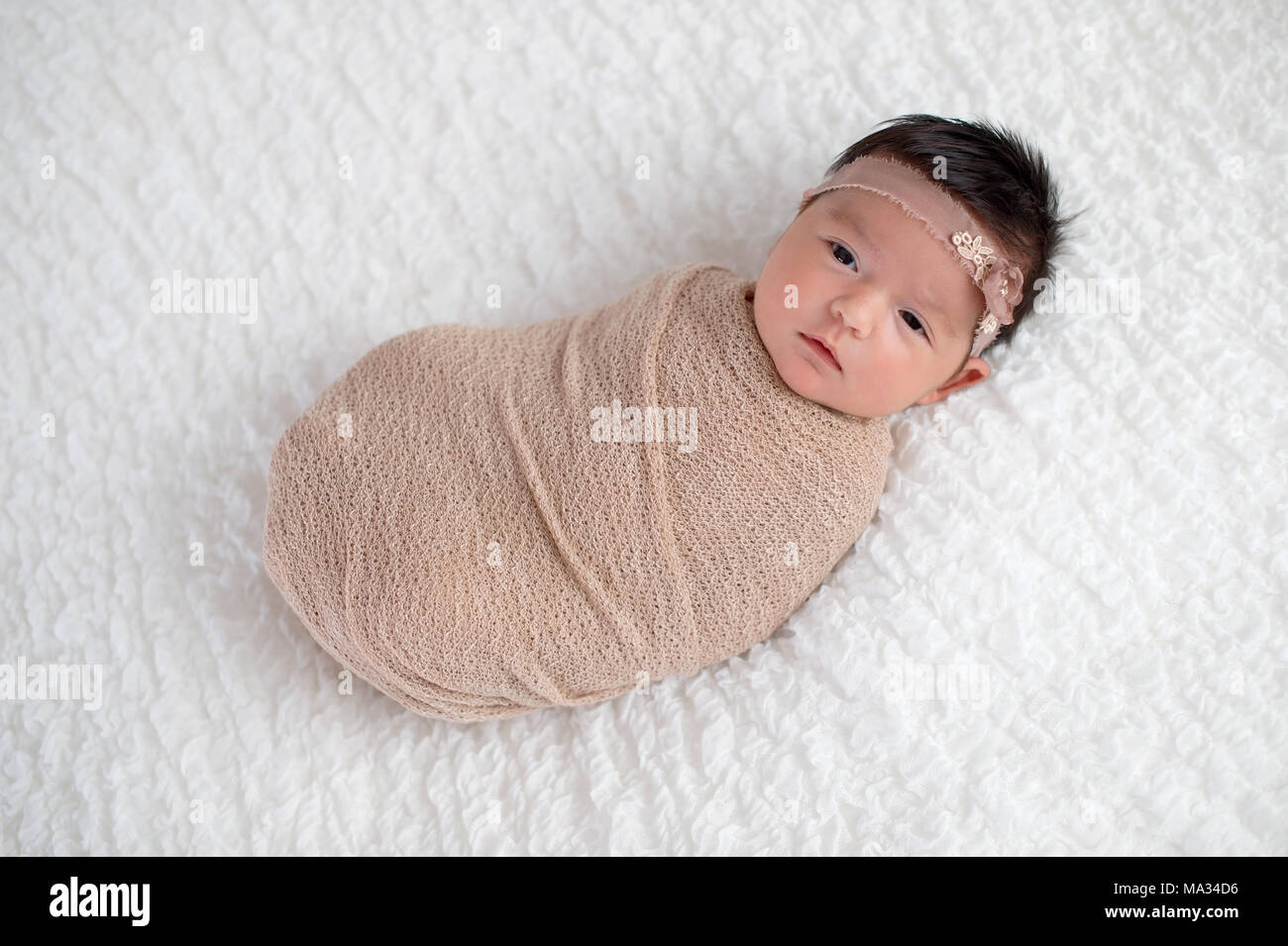 Einen Monat altes Baby girl Gepuckte in Beige wickeln. Im Studio auf einer weißen Decke geschossen. Stockfoto