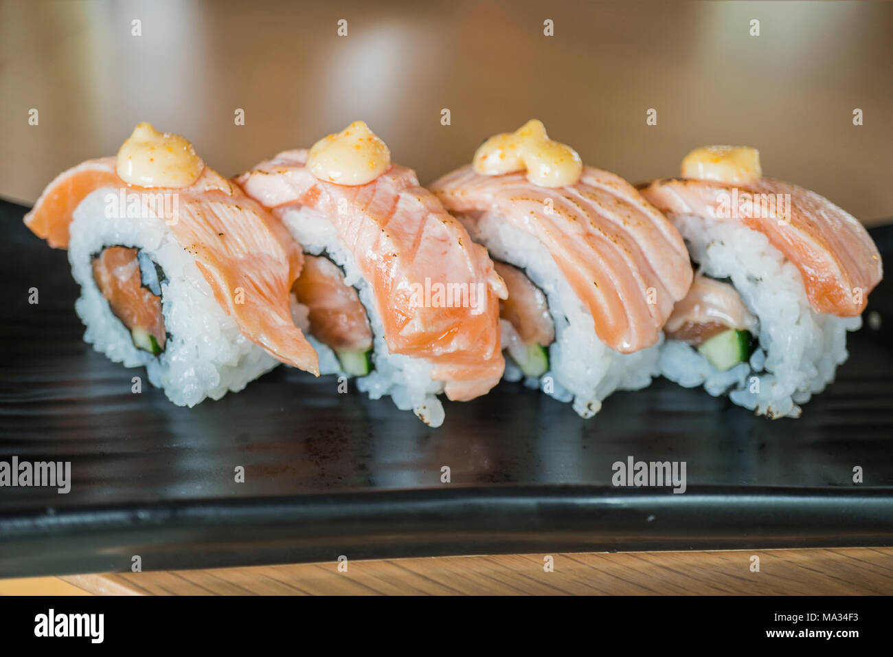 Gegrillter Lachs Sushi Roll, japanisches Essen Stil auf Schwarz Keramik Teller Stockfoto