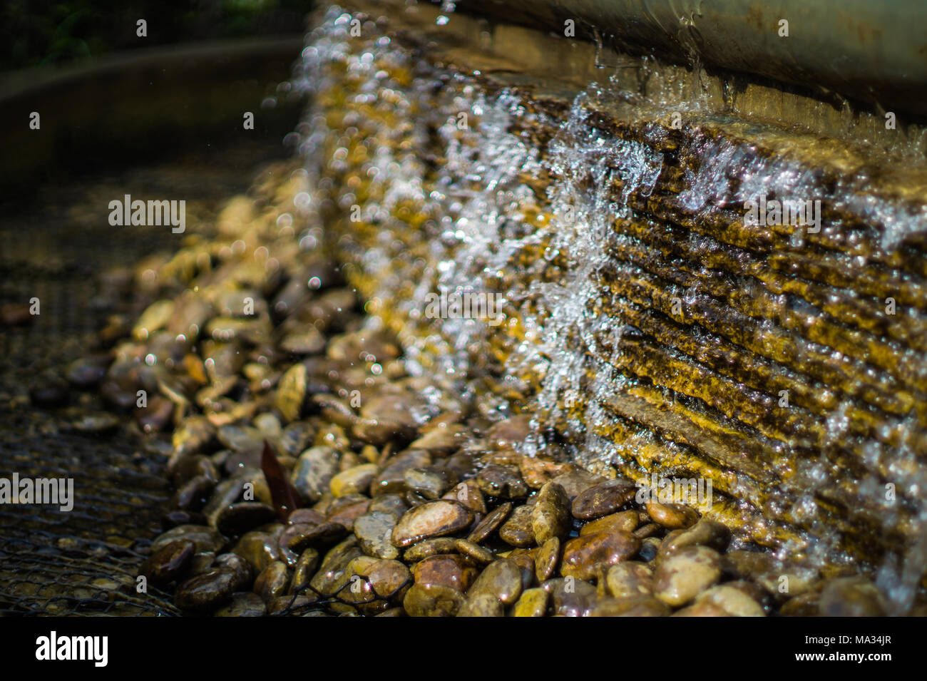 Kleine künstliche Wasserfall mit Splash und Bokeh im Garten Stockfoto