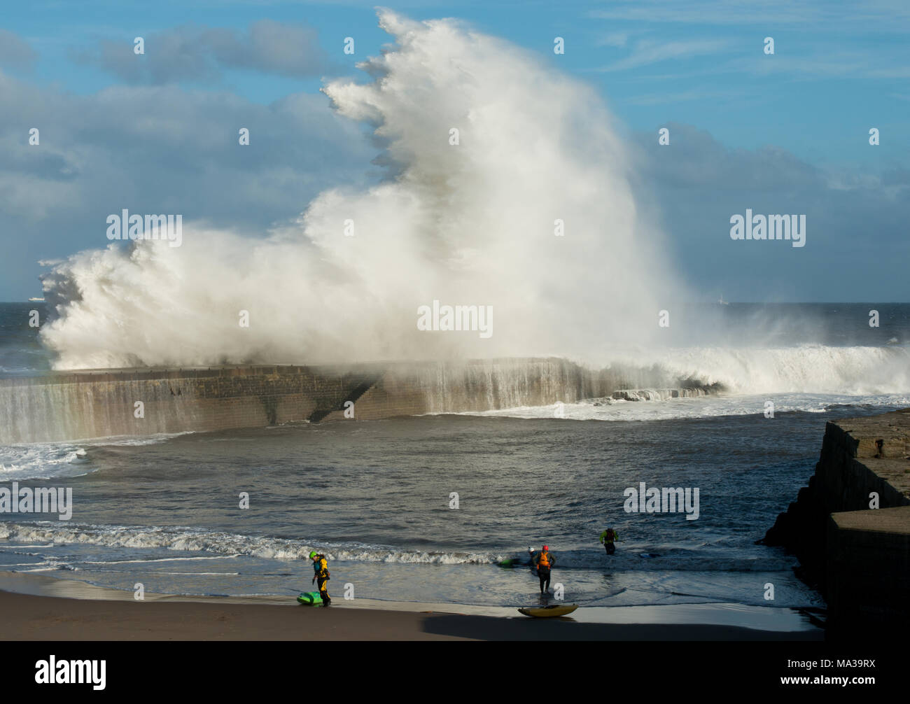 Kajak-Liebhaber betrachten riesige abstürmende Wellen über dem Pier in Seaham im County Durham Stockfoto