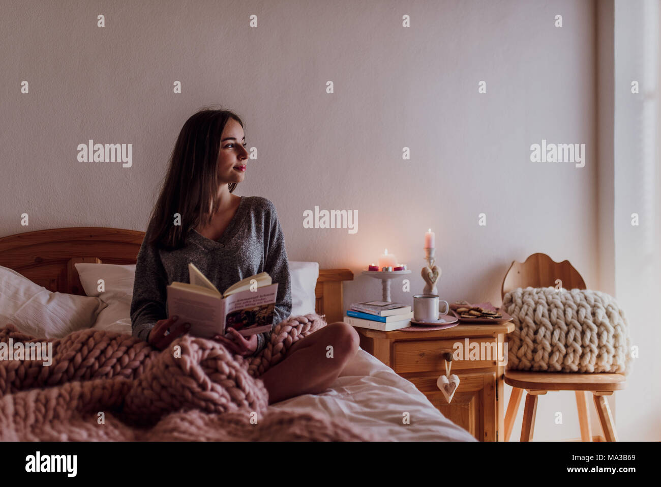 Junge Frau im Bett sitzen und ein Buch lesen Stockfoto